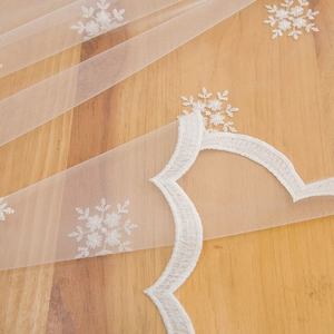Nappe rectangulaire en dentelle blanche avec broderie de flocons sur table en bois