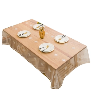 Nappe rectangulaire en dentelle blanche avec motifs de flocons brodés sur table en bois