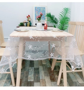 Detailed close-up of white floral lace tablecloth with delicate mesh embroidery