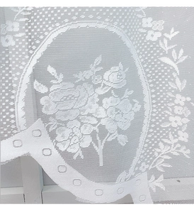 Close-up of white lace curtain showing rose pattern and wavy scalloped edge detail