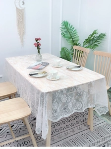 Close-up of white lace tablecloth with floral patterns draped on a rectangle table