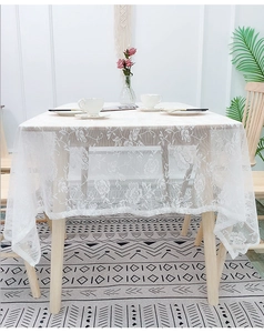 Close-up of white lace tablecloth with floral rose embroidery and scalloped edges