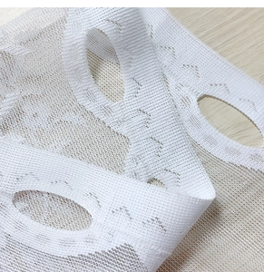 Close-up of white lace curtain fabric showing detailed mesh texture and hollow design