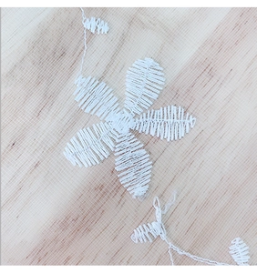 Macro shot of white Nordic lace mesh tablecloth featuring delicate floral embroidery detail