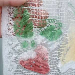 Close-up of white lace curtain fabric showing red strawberry prints and fine mesh texture
