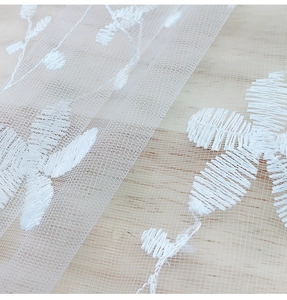Close-up of white floral embroidery on transparent lace mesh fabric with detailed texture