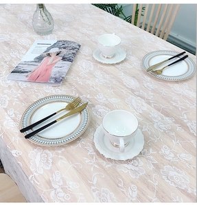 Close-up detail of white lace tablecloth featuring elegant rose embroidery and mesh fabric