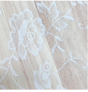 Close-up of white lace tablecloth featuring intricate rose patterns on fine mesh fabric