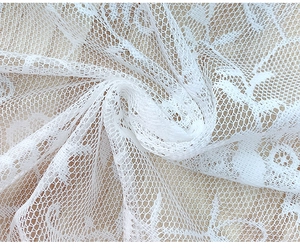 Detailed macro view of white floral lace fabric with intricate mesh patterns on wood