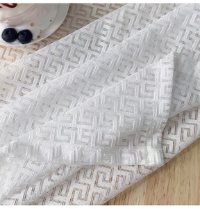 Detailed close-up of white mesh fabric with elegant 3D geometric meander patterns