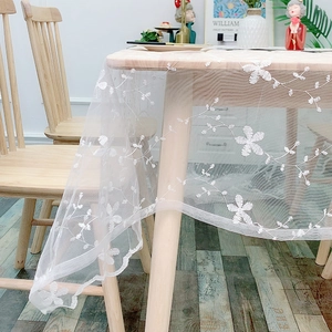 White lace rectangular tablecloth with delicate flower embroidery and mesh texture