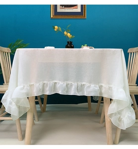 Detail of white semi-transparent tablecloth featuring elegant ruffled hem and rustic fabric