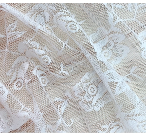 Close-up of white lace tablecloth showing detailed rose patterns and hexagonal mesh texture