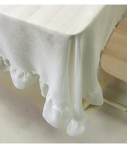 Detail of white Nordic tablecloth featuring delicate ruffled edges and textured fabric