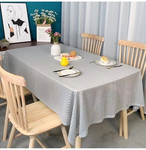 Close-up of light grey tablecloth with Greek key pattern on a wooden dining table