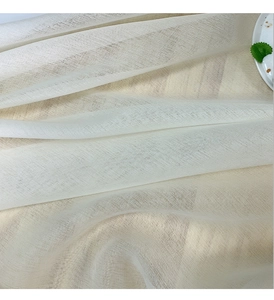 Close-up of light beige linen tablecloth fabric with natural texture and soft drapes