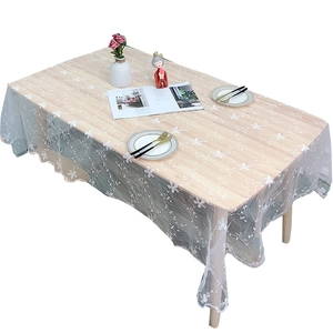White floral lace tablecloth on rectangular wooden dining table with elegant decor