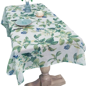 Floral print linen tablecloth with green leaves and blue flowers on a wooden table