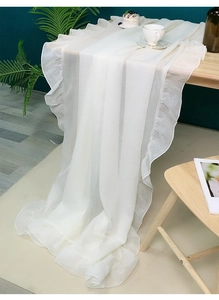 Close-up of white chiffon tablecloth featuring elegant ruffled edges on a wooden table