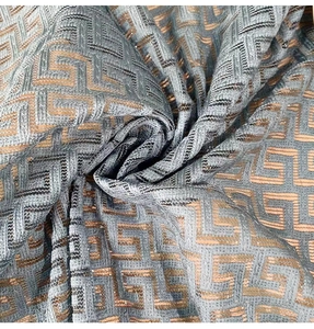 Detail of grey-blue jacquard fabric with golden geometric maze pattern texture
