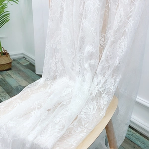 Minimalist white lace tablecloth with floral embroidery draped over a wooden chair