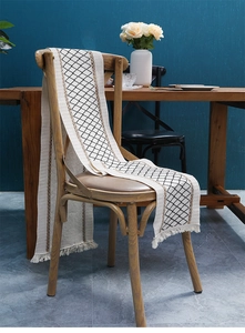 Detailed macro view of bohemian woven cotton linen table runner with tassel and geometric pattern