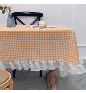 Detail of orange gingham tablecloth featuring delicate white ruffled lace edges