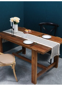 Detail of woven table runner with tassel edges on solid wood table in a home setting