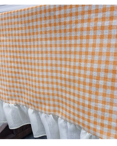 Close-up of orange and white plaid tablecloth featuring decorative white ruffle edges