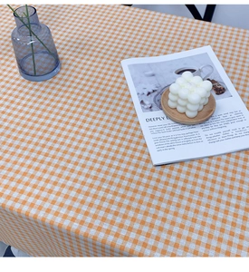 Detailed close-up of orange and white plaid linen tablecloth with lace edge and fabric texture