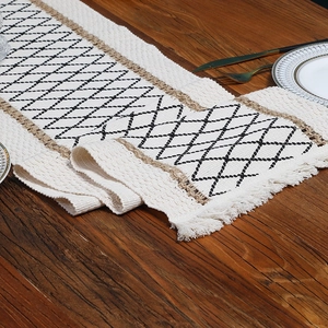Bohemian cream table runner with geometric black patterns and rustic tassels on wood