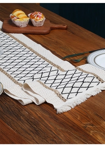Close-up of bohemian linen table runner with black diamond pattern and tassel fringe detail