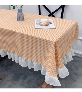 Close-up of orange gingham tablecloth featuring white sheer pleated ruffle lace edges