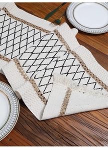 Close-up of woven cotton and jute table runner with geometric patterns and fringe detail