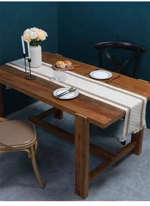 Close-up of woven linen table runner with tassels and brown stripes on wooden dining table