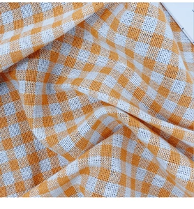 Detailed close-up of orange and white gingham cotton linen tablecloth with fine texture