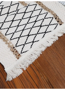 Macro detail of woven table runner with black geometric patterns and long fringes