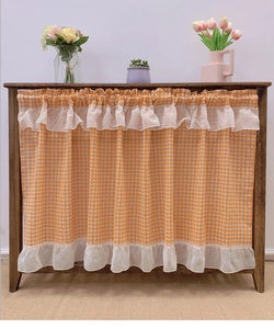 Close-up of orange gingham cabinet curtain with elegant double-layered cream ruffles