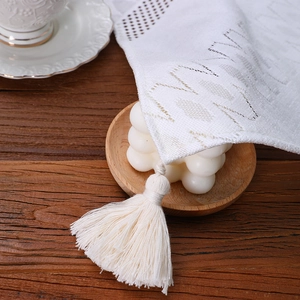 Elegant white lace table runner with geometric hollow patterns and fringe on wooden table