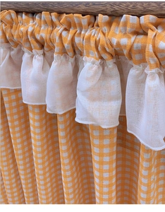 Detailed view of yellow plaid fabric curtain with white lace ruffle edge and pleats