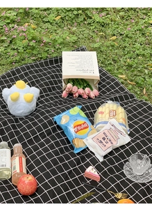 Close-up of a classic black and white checkered picnic mat on lush green grass outdoors