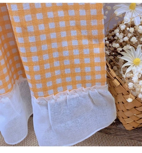Close-up of yellow gingham cafe curtain featuring double-layer white ruffle hem detail