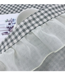 Detail of gingham cotton linen tablecloth featuring delicate white lace ruffle edges