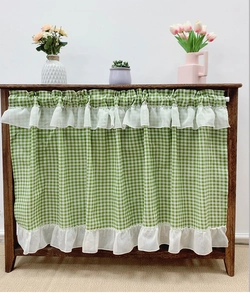 Detail of green and white plaid cafe curtain with white ruffled lace trim on cabinet