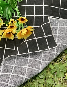 Detail of double-sided black and white plaid picnic mat with fringe on grass