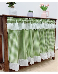 Detail of green gingham cafe curtain with double-layered white lace ruffles and linen texture