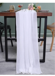 Detail van witte doorschijnende tafelloper met elegante geplooide textuur op houten tafel