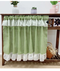 Detail view of green and white checkered cafe curtain with ruffled edges on wooden shelf