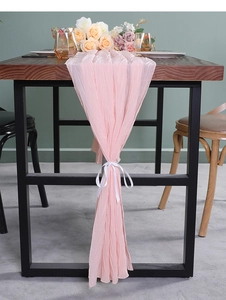 Detail van lichtroze geplooide chiffon tafelloper met witte striksluiting van lint