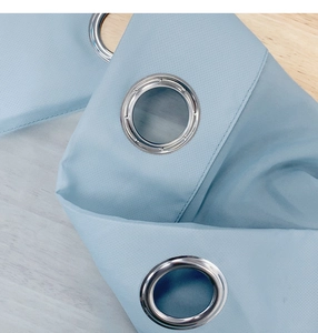 Detail of light blue waterproof gazebo curtain with silver metal grommets on wood background